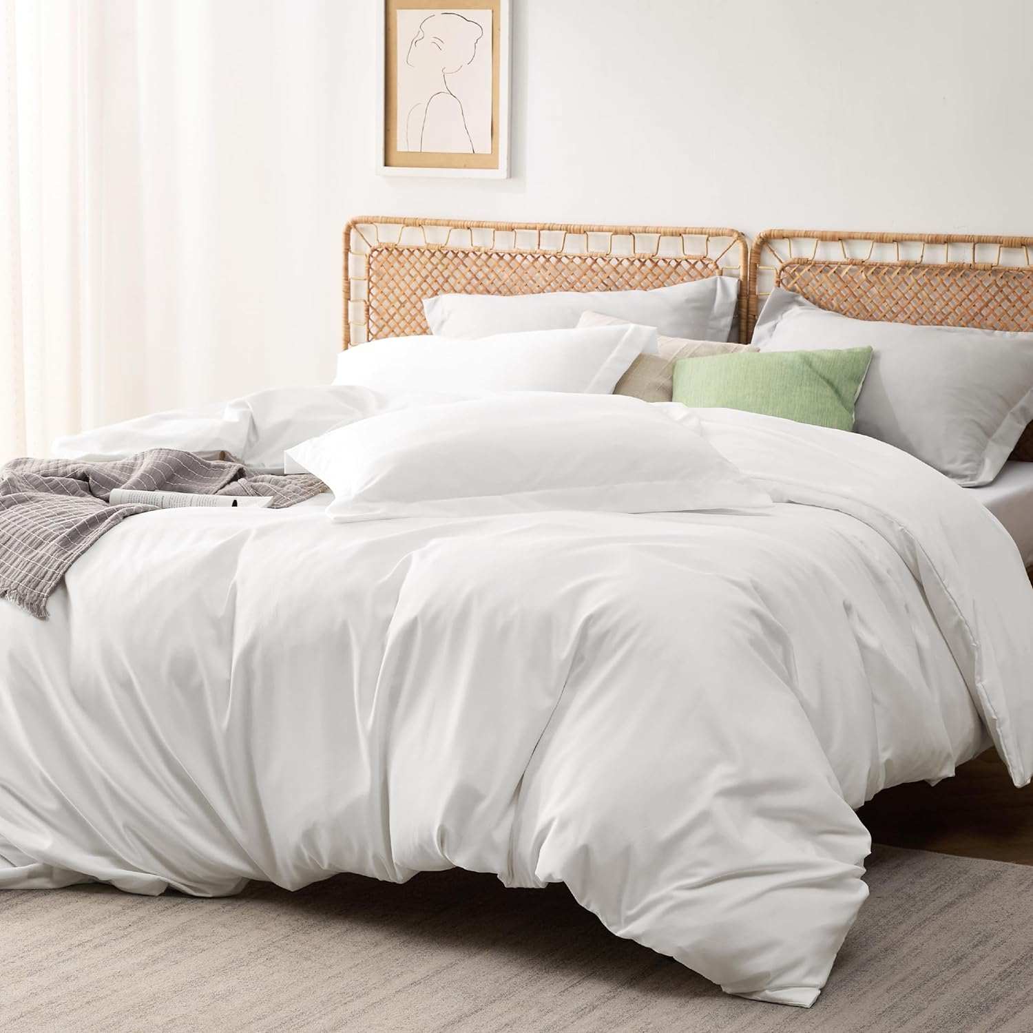 Luxurious white bedding set on a cozy bed with decorative pillows and a rattan headboard in a modern, bright bedroom.