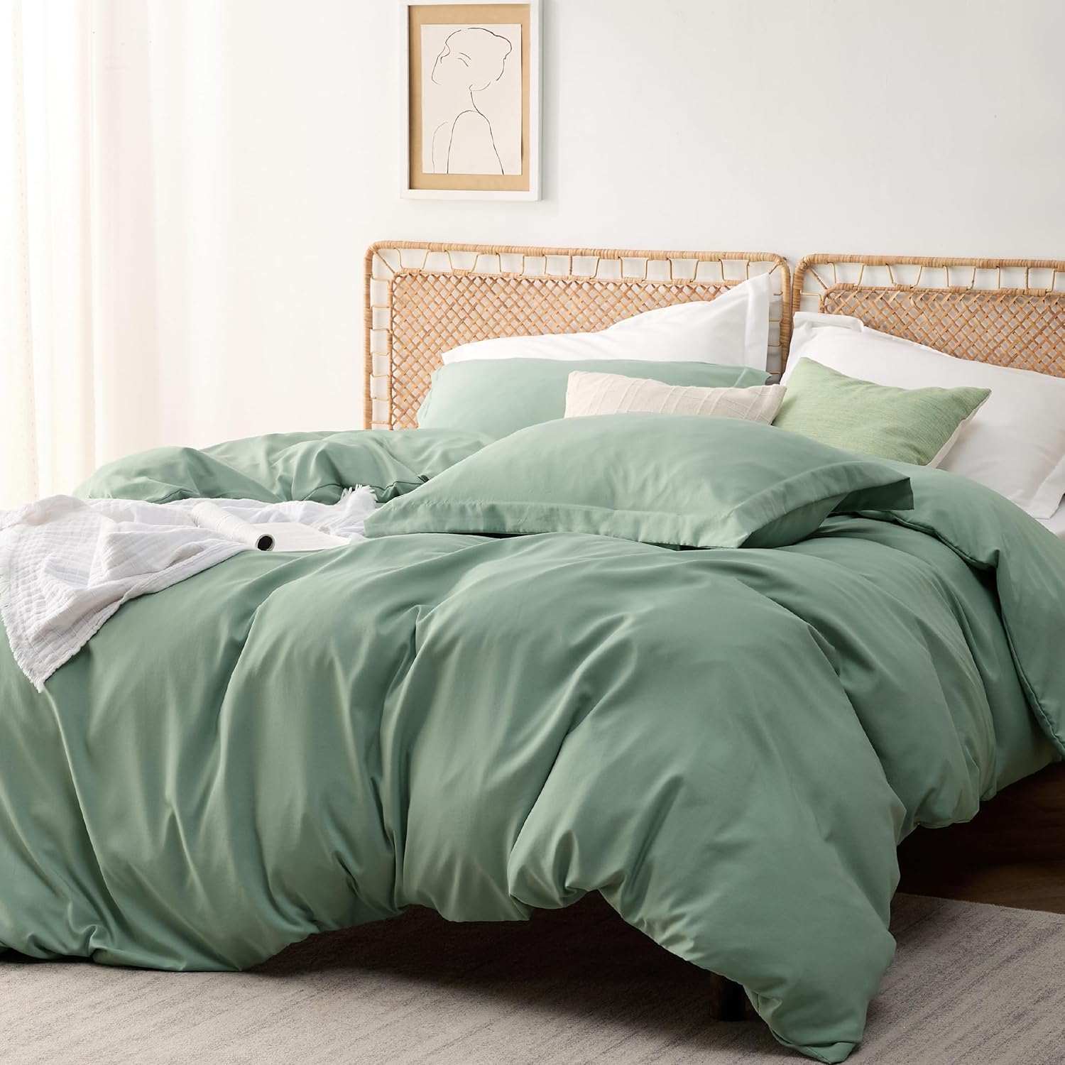 Sage green duvet cover set on a cozy bed with rattan headboard in a minimalist bedroom with natural light.