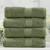 Stack of four green bath towels in front of a window and white tiles