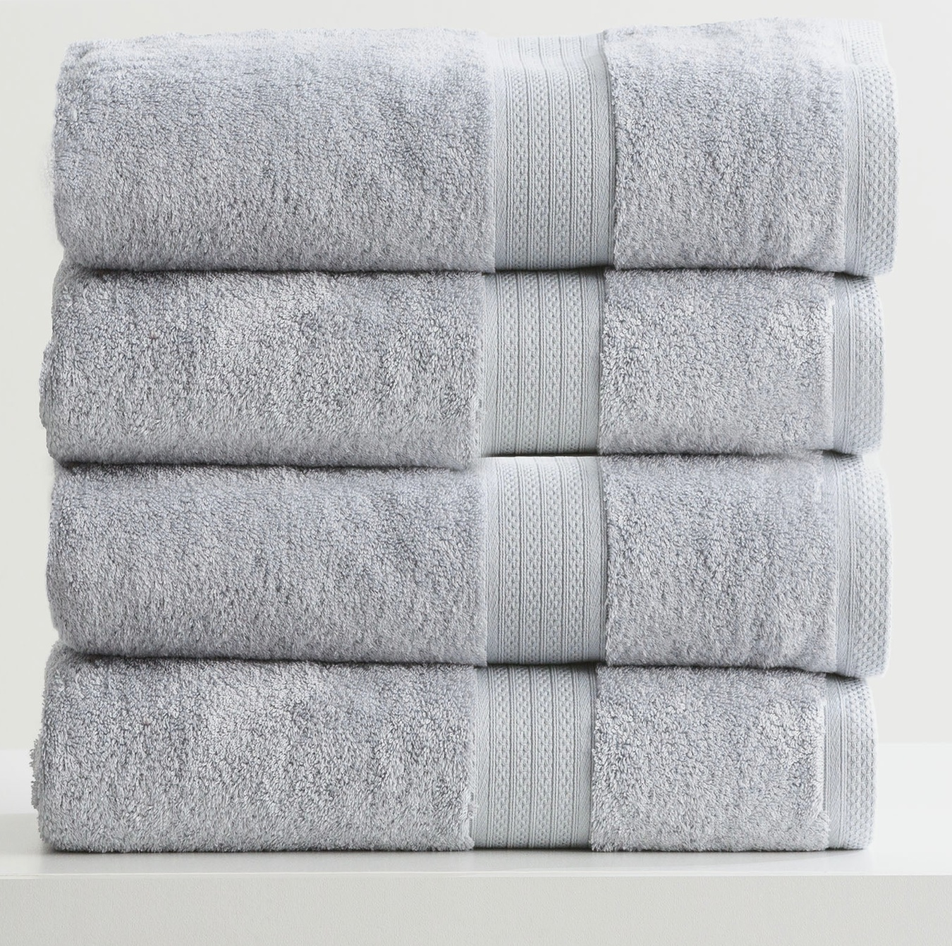 Stack of four folded gray towels with textured stripes, neatly arranged on a white surface.