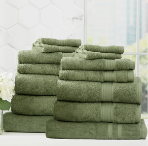 Stack of green bath towels placed beside a window with white tiles and decorative flowers in the background.