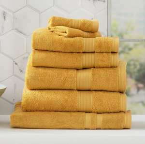 Stack of cozy, yellow bath towels in modern bathroom setting.