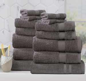 Stacks of plush gray towels in a bathroom with a toothbrush holder and hexagonal tile wall in the background