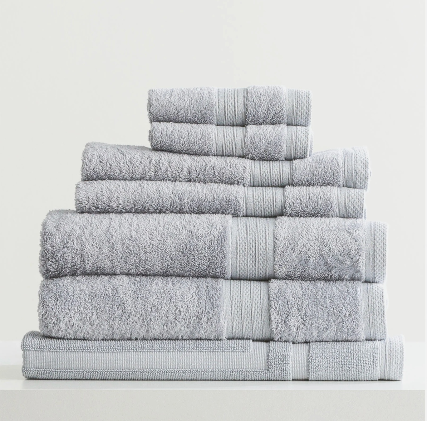 Stack of neatly folded gray towels on a white surface